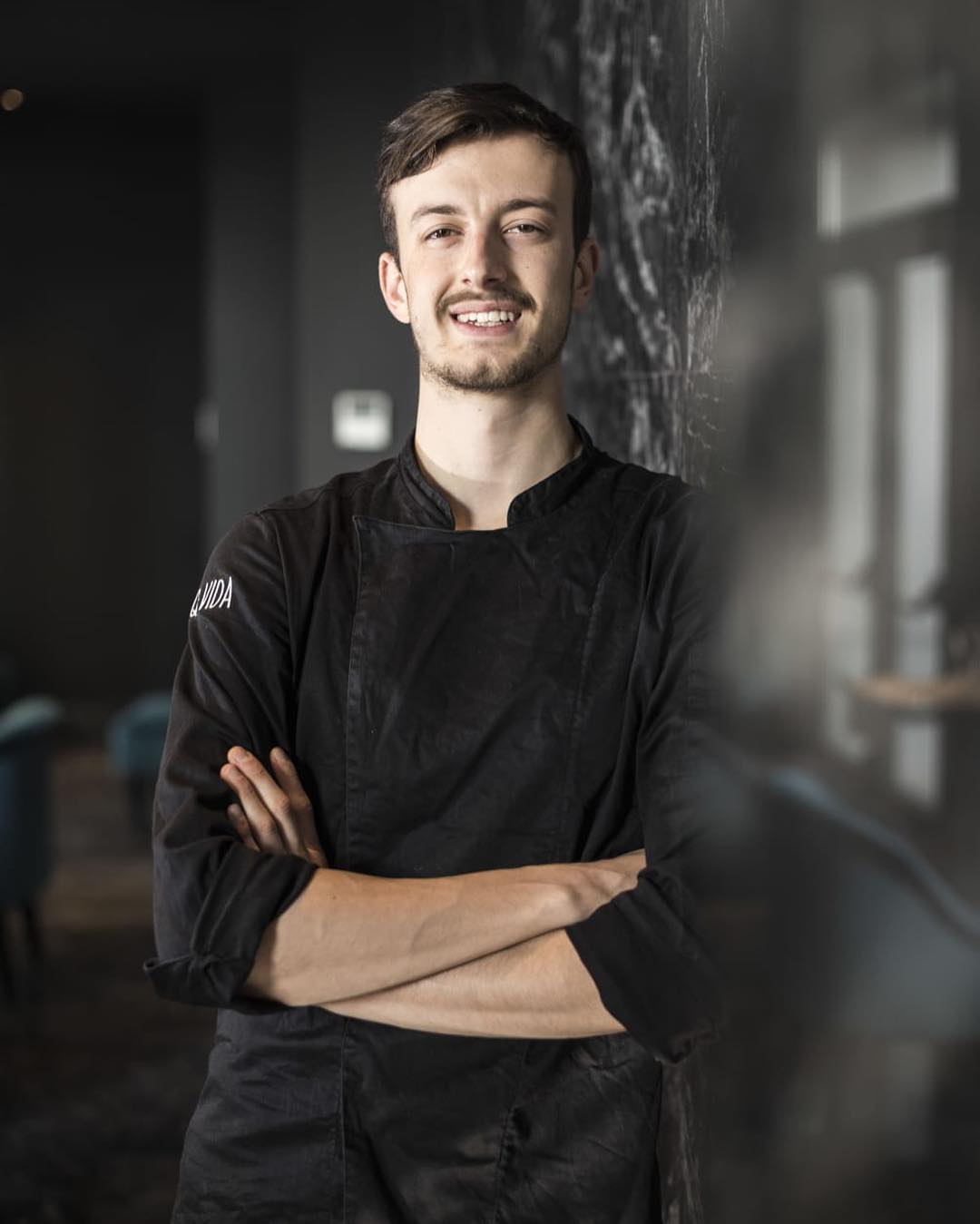Nicola Pepe standing with arms crossed in a black chef coat.