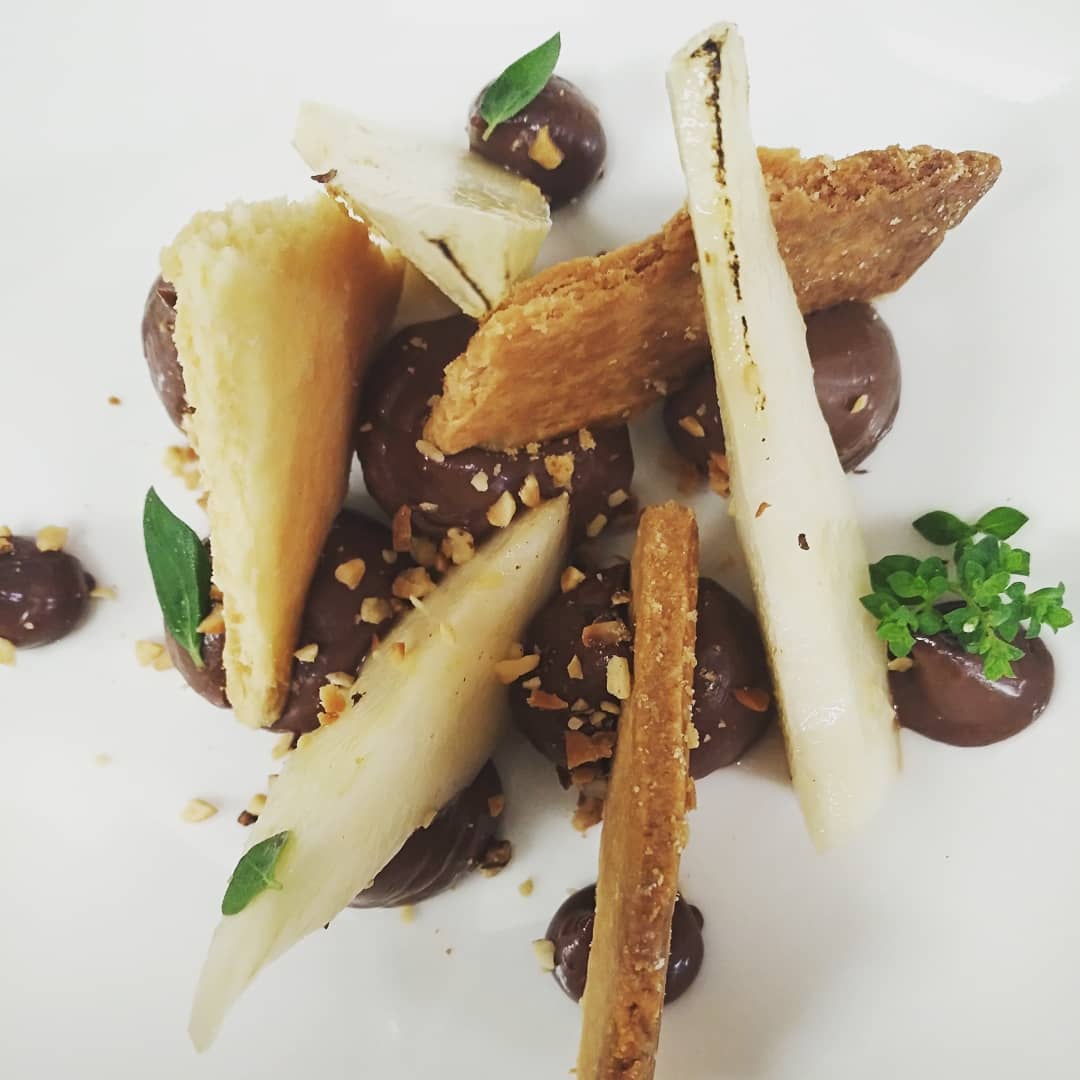 Minimal plated dessert with pear, chocolate, and crisp garnish.